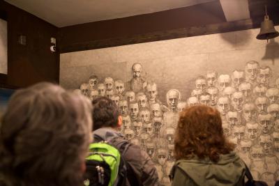Uczestnicy i uczestniczki wyjazdu studyjnego na wystawie Mariana Kołodzieja - Uczestnicy i uczestniczki wyjazdu studyjnego przyglądają się rysunkowym portretom o zniekształconych, gadzich rysach twarzy więźniów obozów koncentracyjnych na wystawie Mariana Kołodzieja, Oświęcim 2019. 